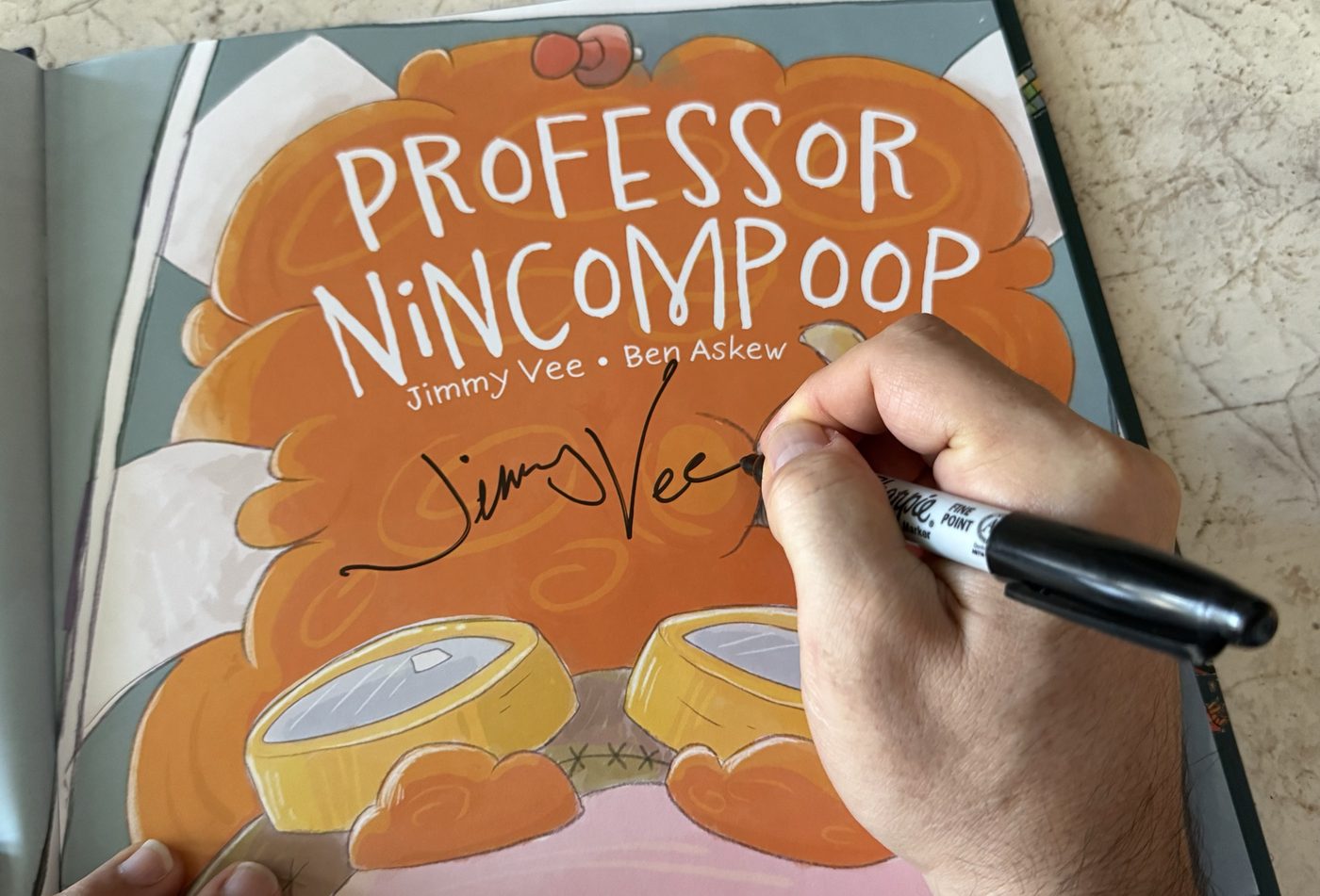 Jimmy Vee hand-signing the title page of Professor Nincompoop